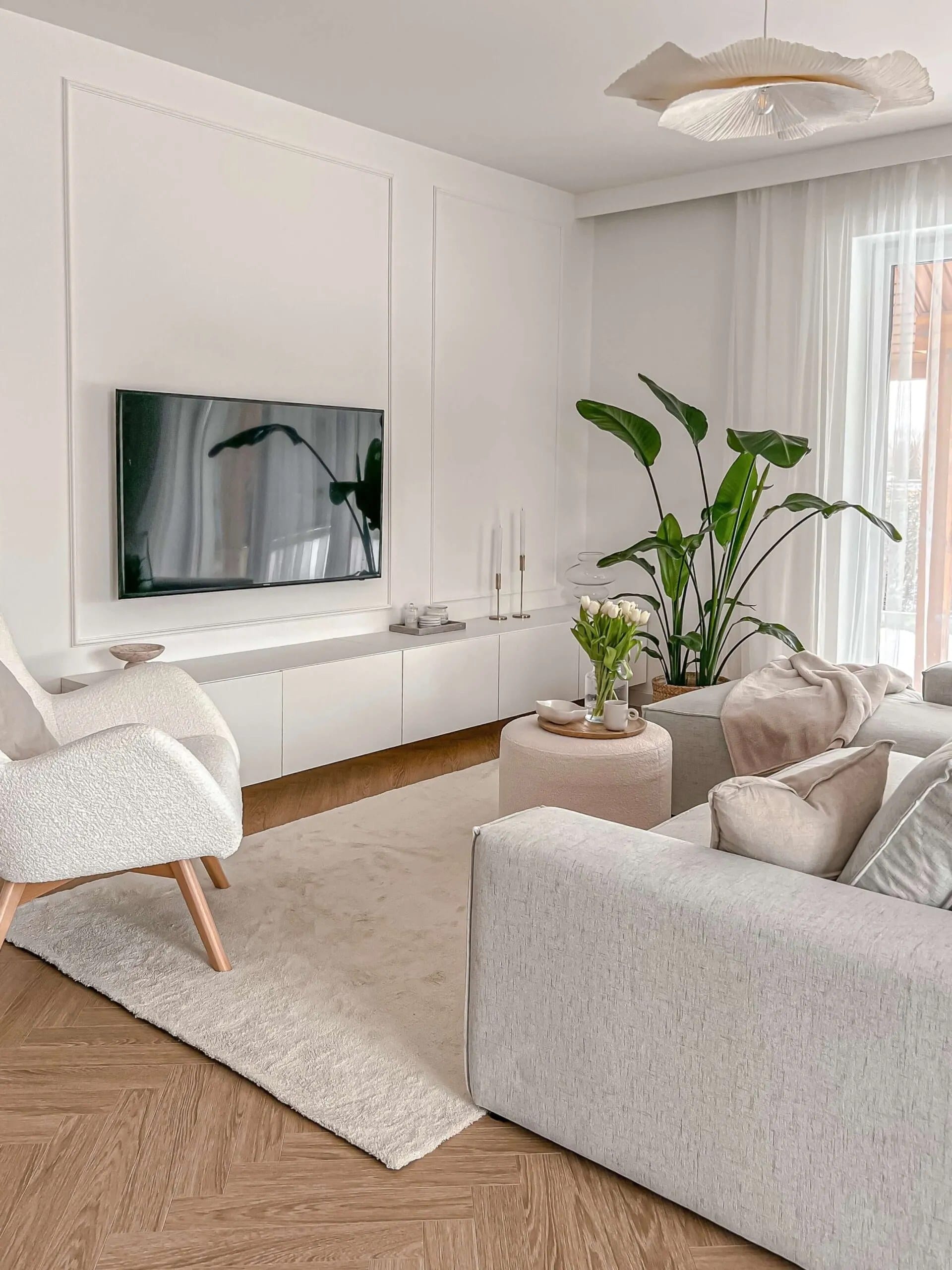 Jasny salon z firaną od sufitu i ścianą TV